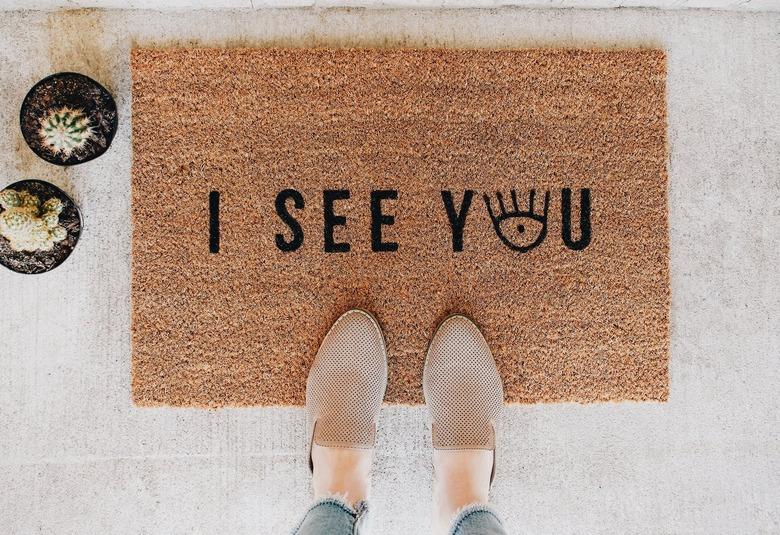 a woman's shoes on a brown doormat with black letters spelling 