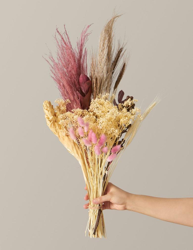 person holding dried floral arrangement