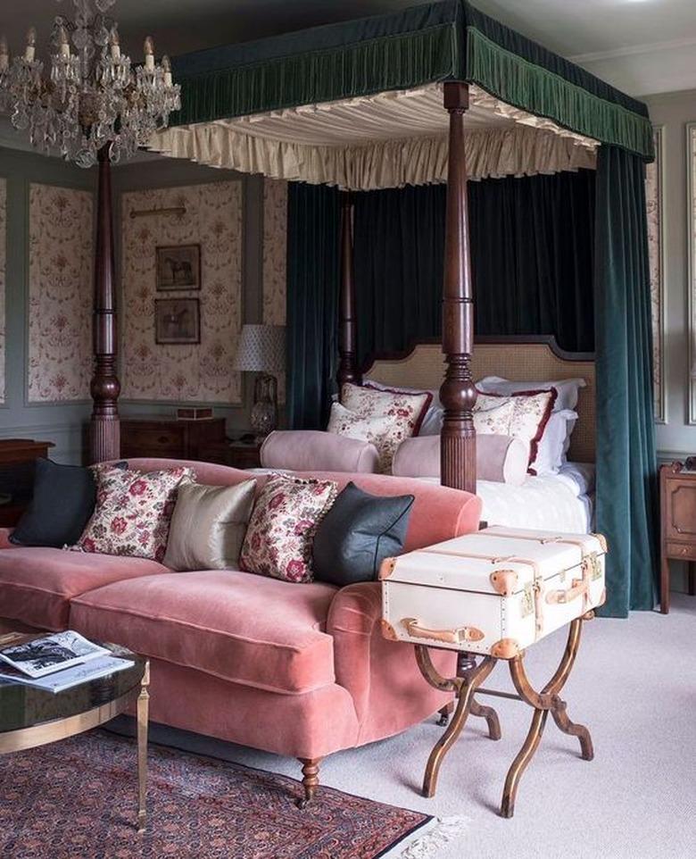 country bedroom idea with four poster bed with velvet curtains and velvet sofa