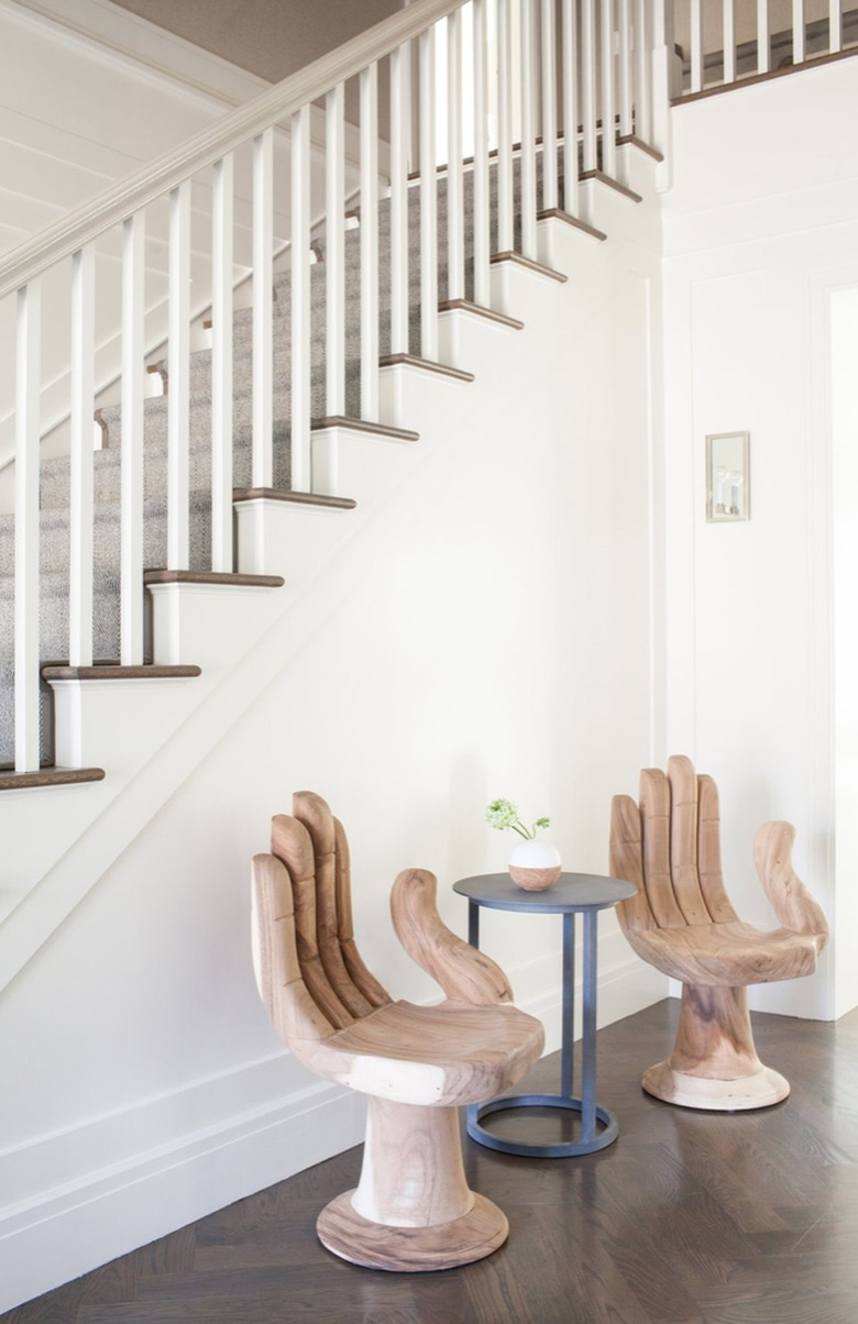 Entryway with modern chairs, table, stairway.