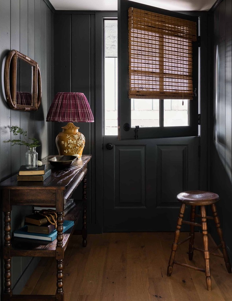 Entryway with dark gray paint, console table, stool, wood floors.