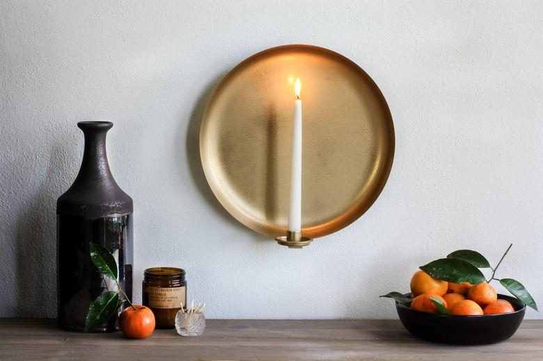 Wall sconce with candle with bowl of tangerines and brown vase