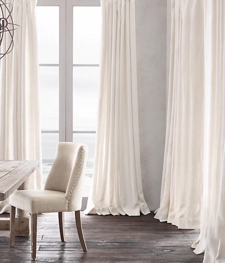 White linen curtains, wood floor, chair, table.