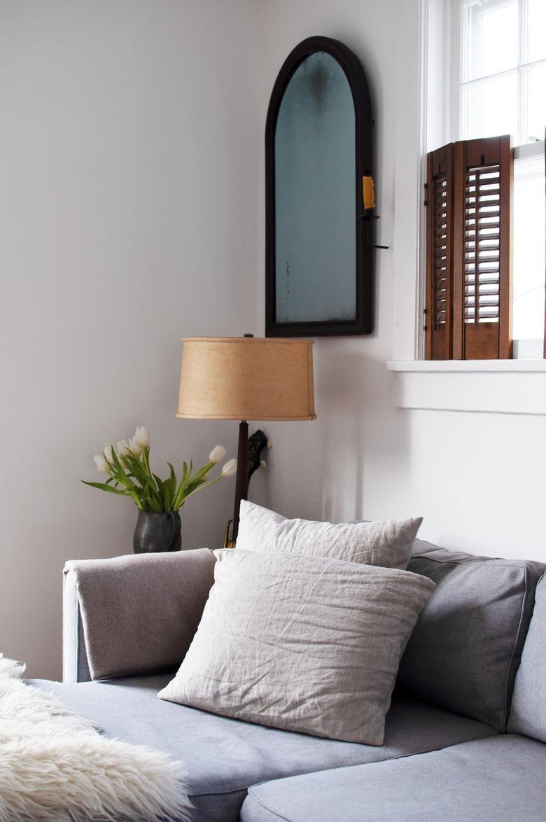 Gray sofa in white walled living room with brown shutter windows