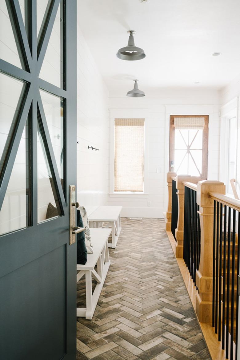 Warm wood and black wrought iron farmhouse stair railing in breezeway