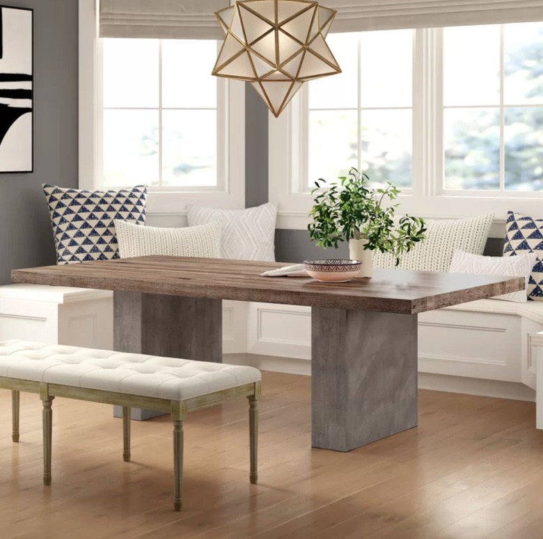 Wood dining table with concrete base, dining bench, built-in dining nook, pendant light.