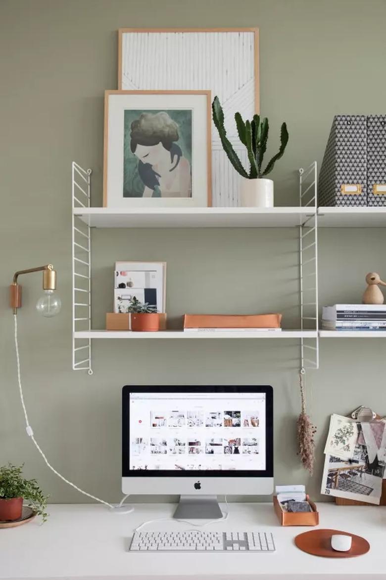 Feng Shui Home Office with open shelving, green walls, and wall light fixture