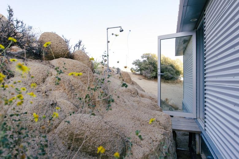 a glass door is open on the side of a pre-fab home made of corrugated metal