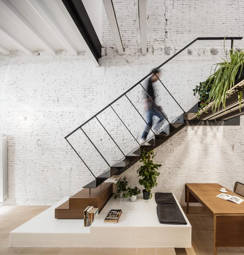 white brick house with floating stairs and desk underneath