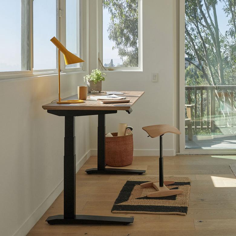 standing desk with lamp and stool near window