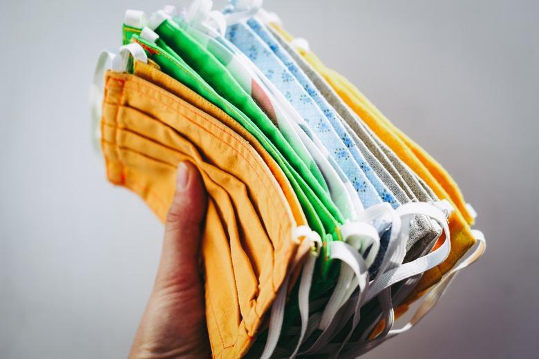 person holding colorful face masks