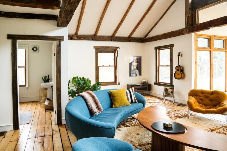 blue curved couches with a curved coffee table on a floor with rustic planks and a southwestern-patterned rug