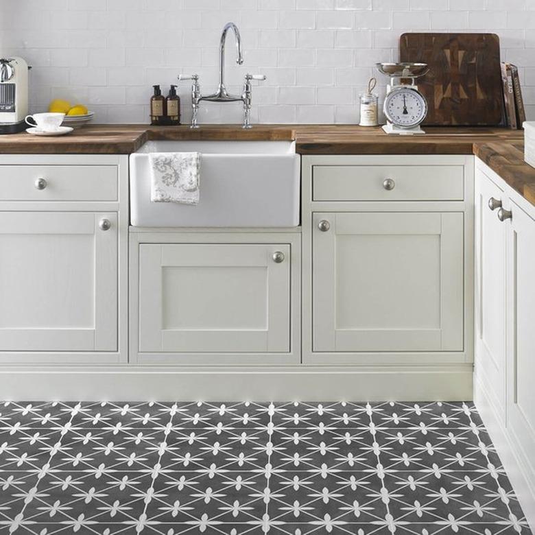 white kitchen with wooden countertops and retro gray flooring