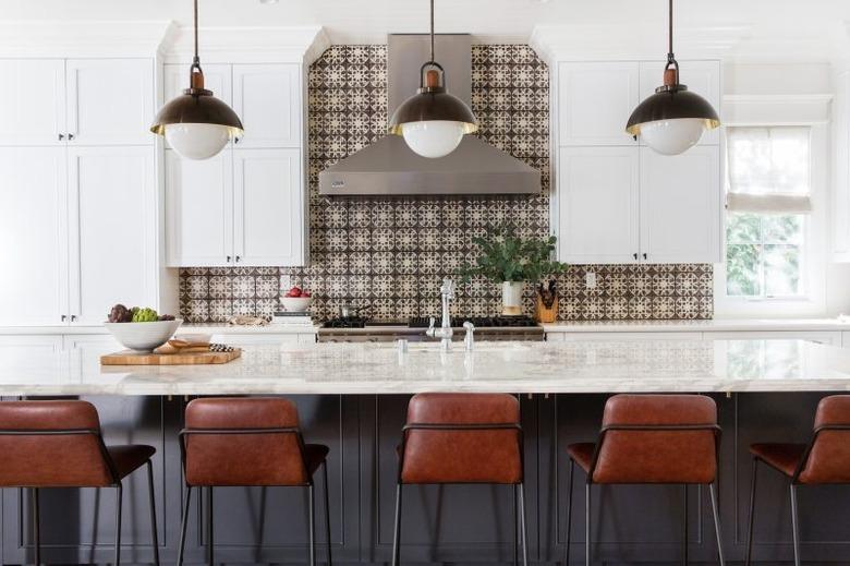 long wooden gray kitchen island with leather bar chairs and intricate tile backsplash