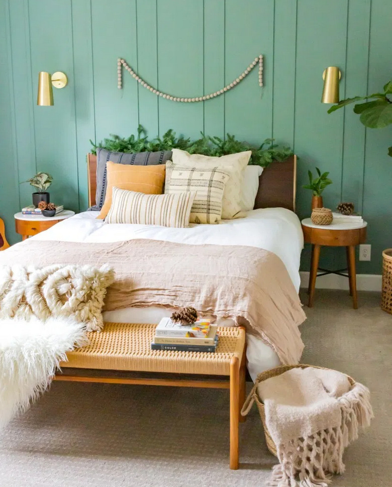 Green boho room with green board and batten accent wall and neutral bed linens