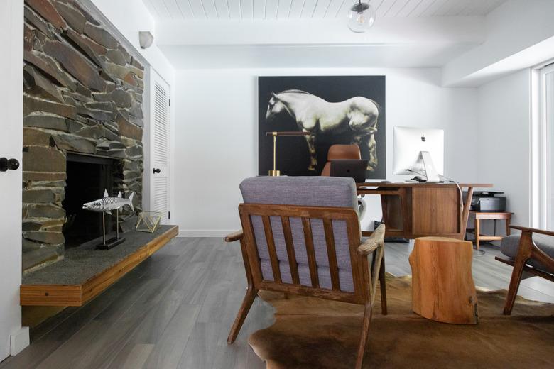 gray hardwood floor colors in living room with stone fireplace and cowhide rug