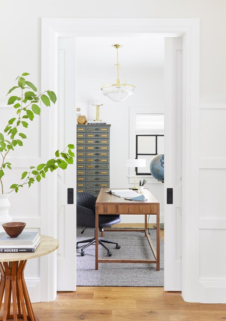 white home office with vintage decor and glass pendant light