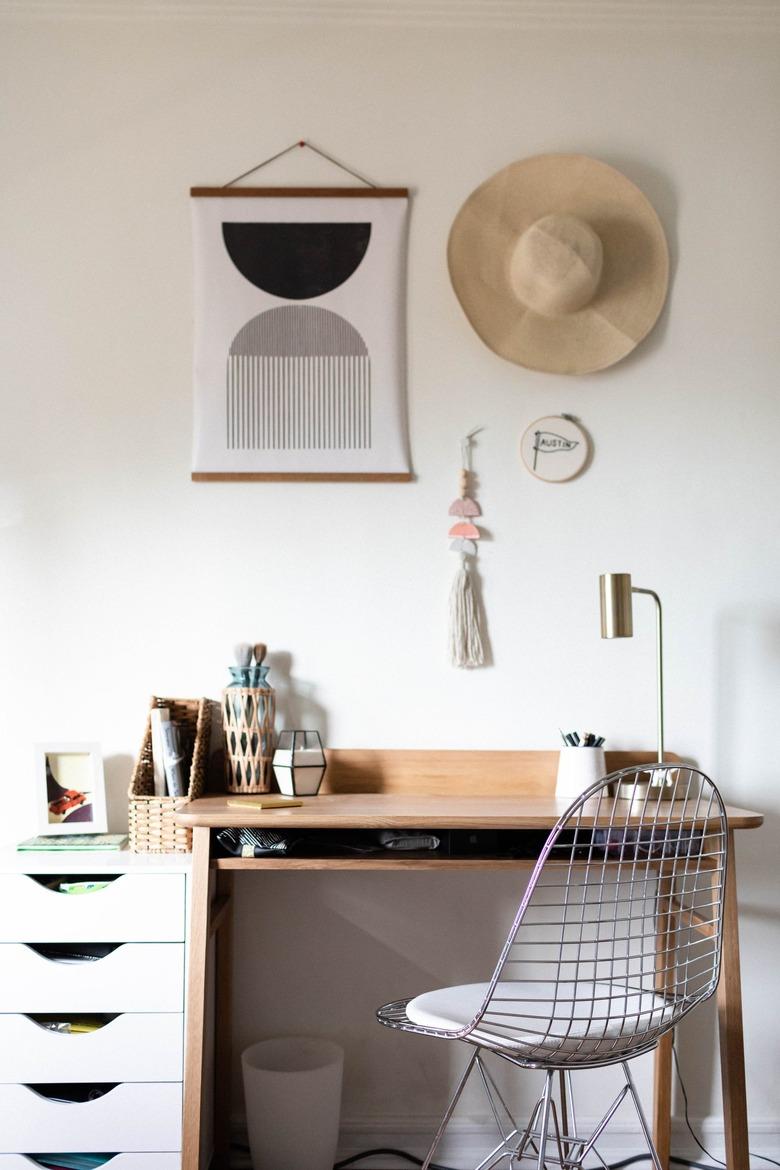 A wood desk with white drawers and a retro wire chair