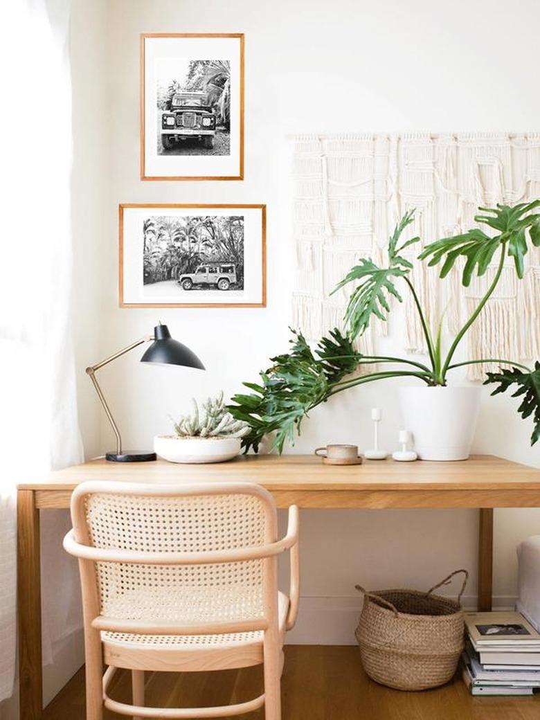 a neutral office with black and white photos and macramé on the wall