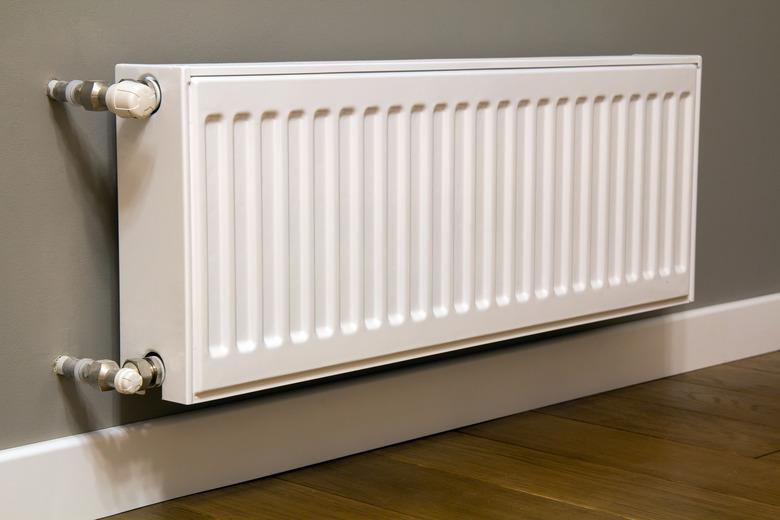 White metal heating radiator mounted on gray wall inside a room.