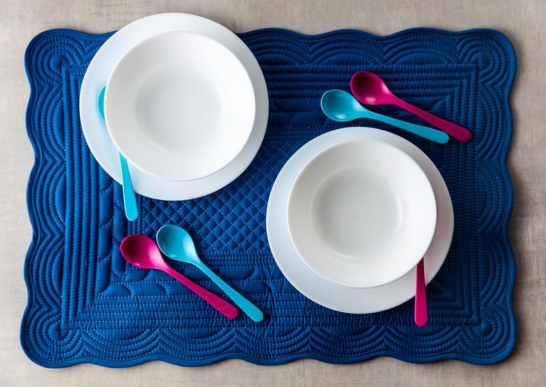 A set of baby dishes on a blue soft napkin for breakfast. kitchen table accessories for serving. Colored small spoons.