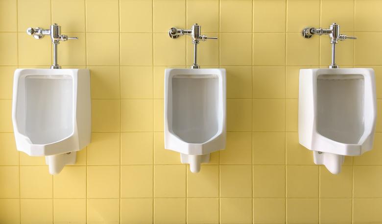 Close up row of outdoor white urinals men on yellow of wall public toilet.