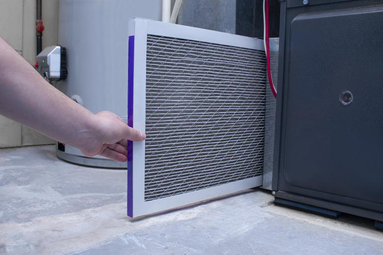 A person changing an air filter on a high efficiency furnace