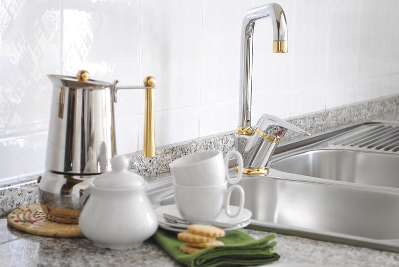 Stainless double kitchen sink with brass-accented faucet.