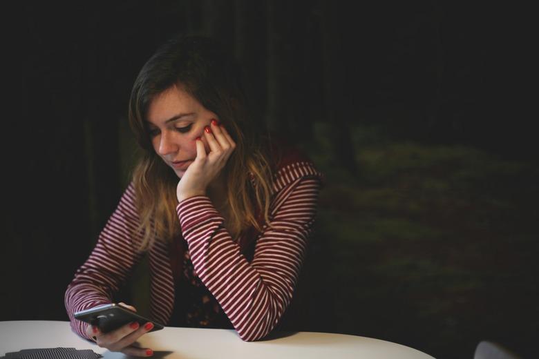 woman sitting at table holding smartphone