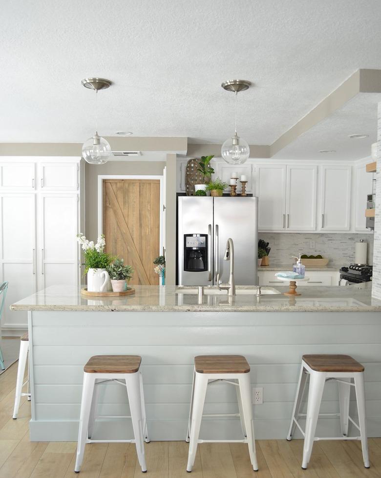 white rustic kitchen with wood barn door and glass pendants over the island