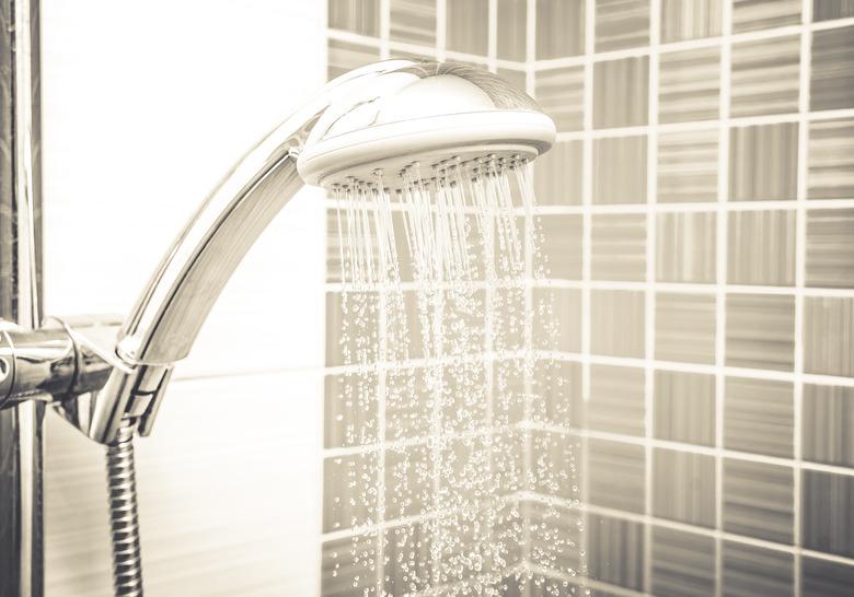 Fresh shower where water running from shower head and faucet in modern bathroom. Sepia