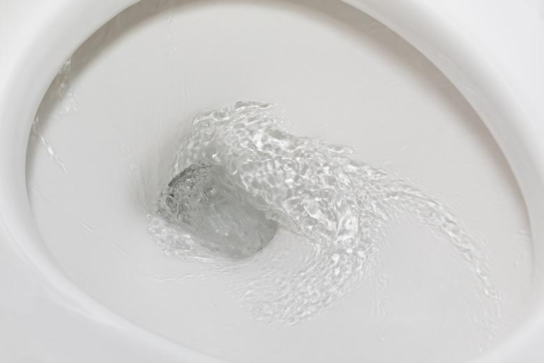 Motion blur of flushing water in toilet bowl. Plumbing, home repair, and water conservation concept.