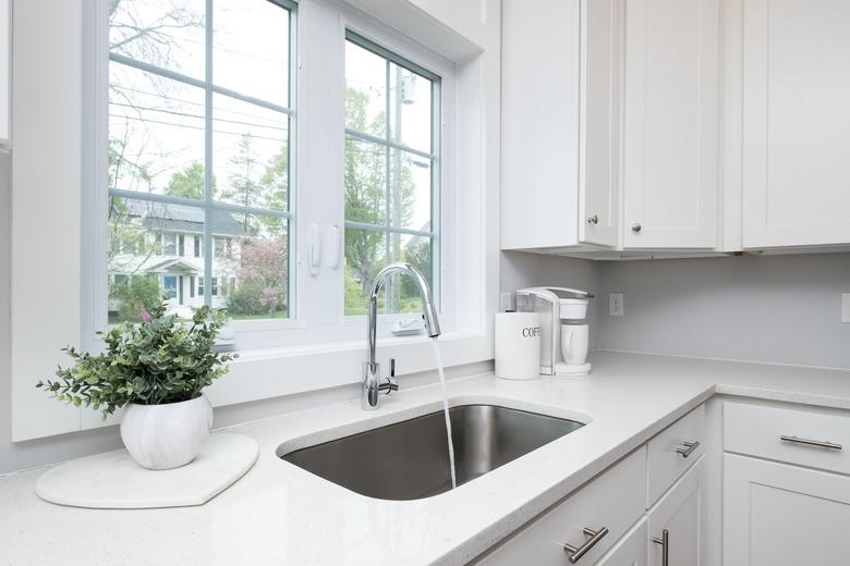 Photograph of a kitchen sink faucet with water running.