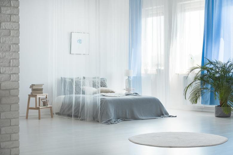 Bright, airy blue and white bedroom with sheer curtains.