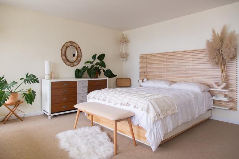 white bed with light wood furniture, furry rug, and plants