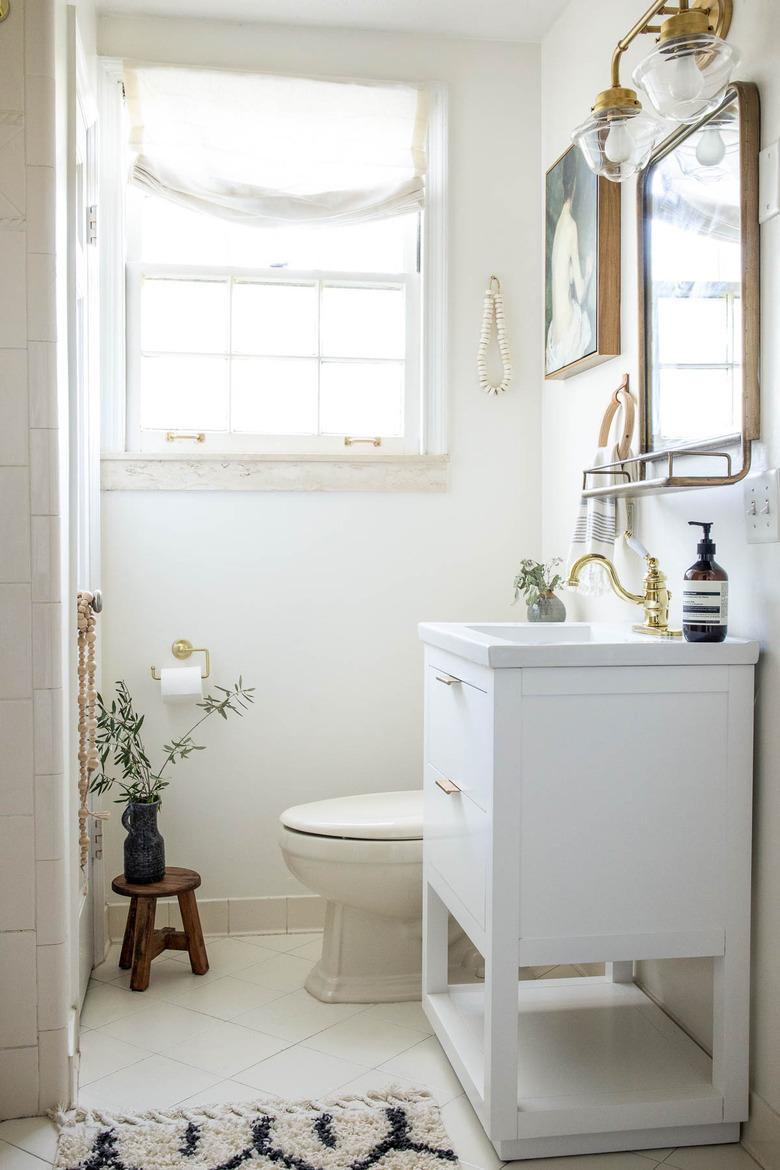 Small bathroom with Walmart white vanity sink and brass mirror and sconces