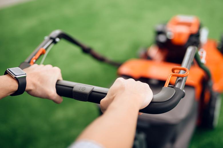 A man holds a lawn mower for the handle.