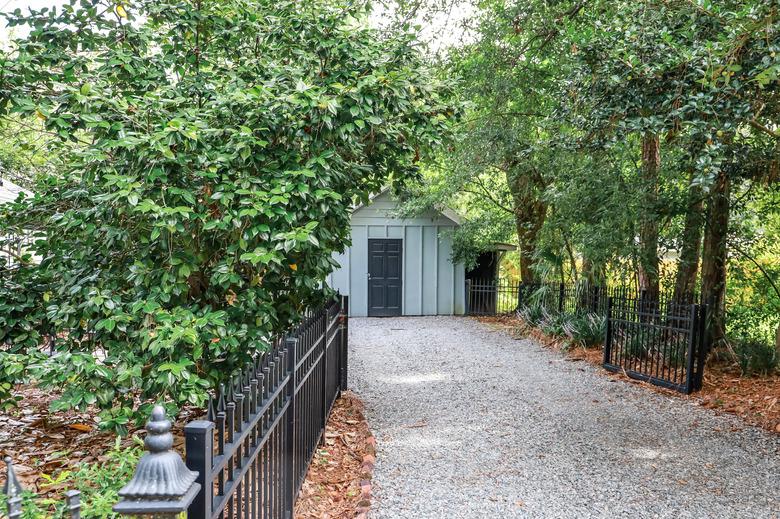 Gravel driveway with fence and storage shed.