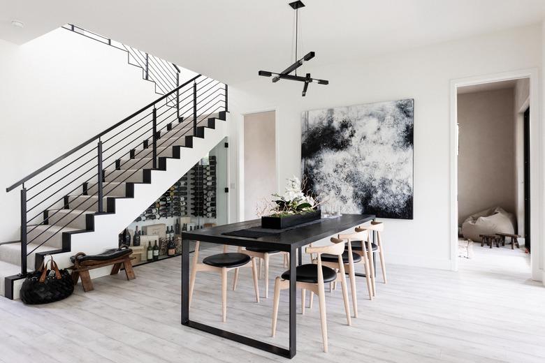 grey monochrome dining room with modern art. view of stair case and hardwood floors