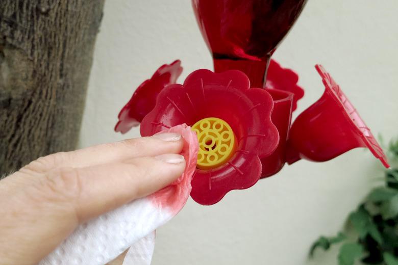 Wiping down a hummingbird feeder.