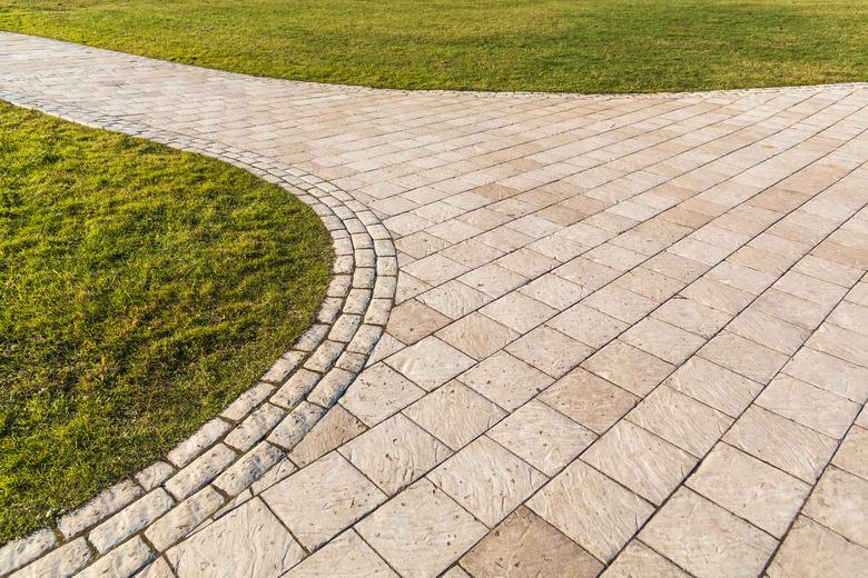 Curved path in the shape of a wave on the grass in a park. Pavers of different shapes.