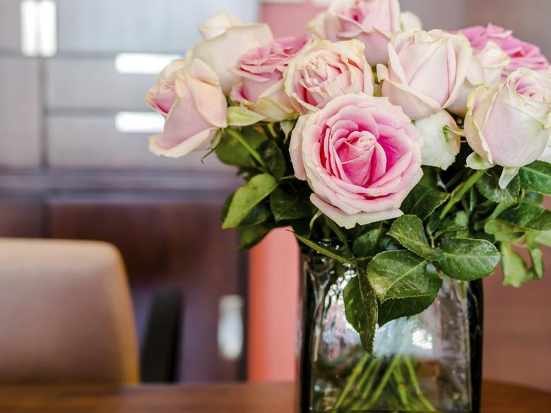 Wooden working table with vase of roses in modern office