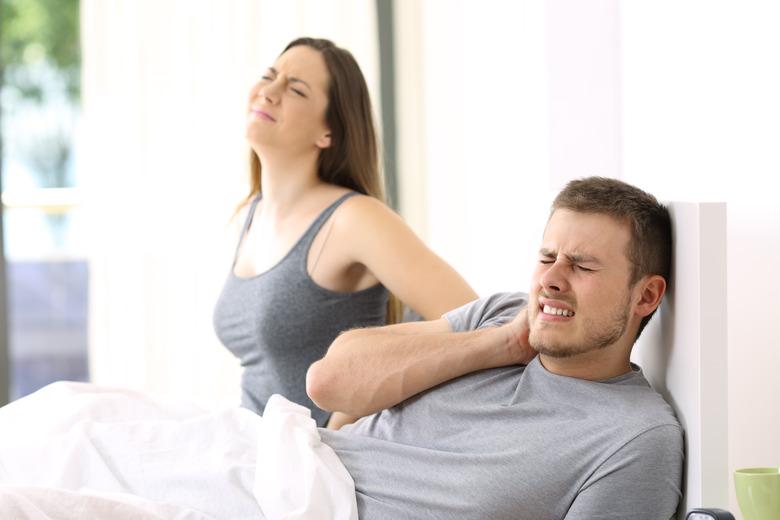 Couple suffering ache in an uncomfortable bed.