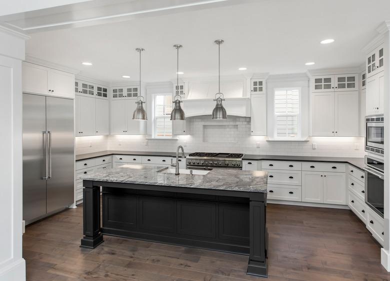 beautiful kitchen in new luxury home with island, pendant lights, stainless steel appliances, and hardwood floors