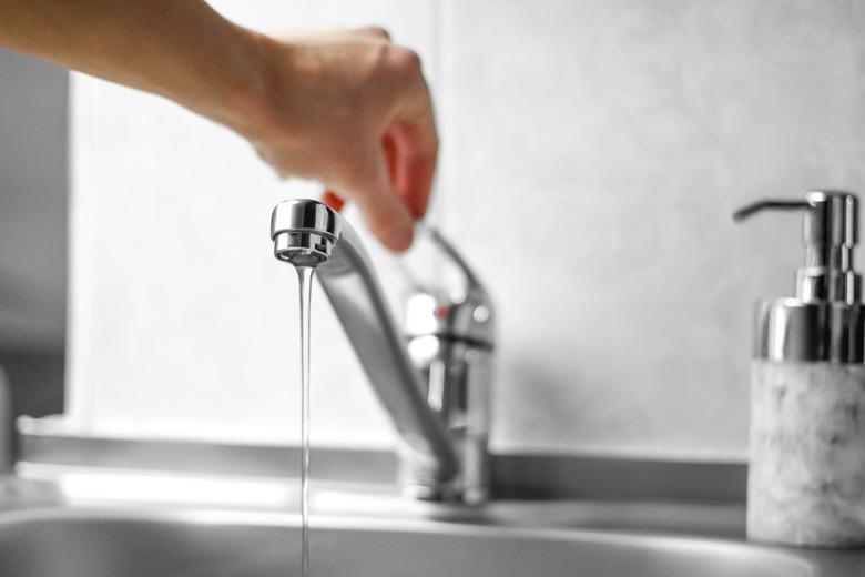 Hand opens the water tap. Close up