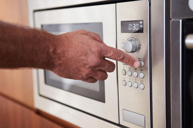 Close-up of hand using microwave