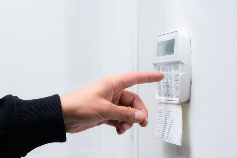 Hand of person entering alarm system code for apartment, house or business office