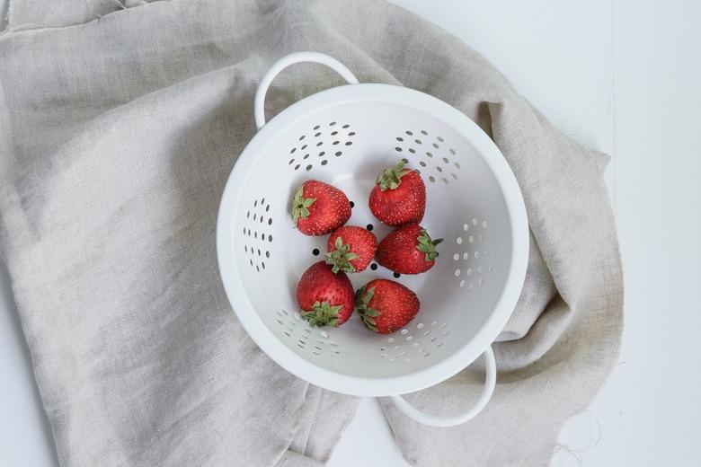 strawberries in white colander