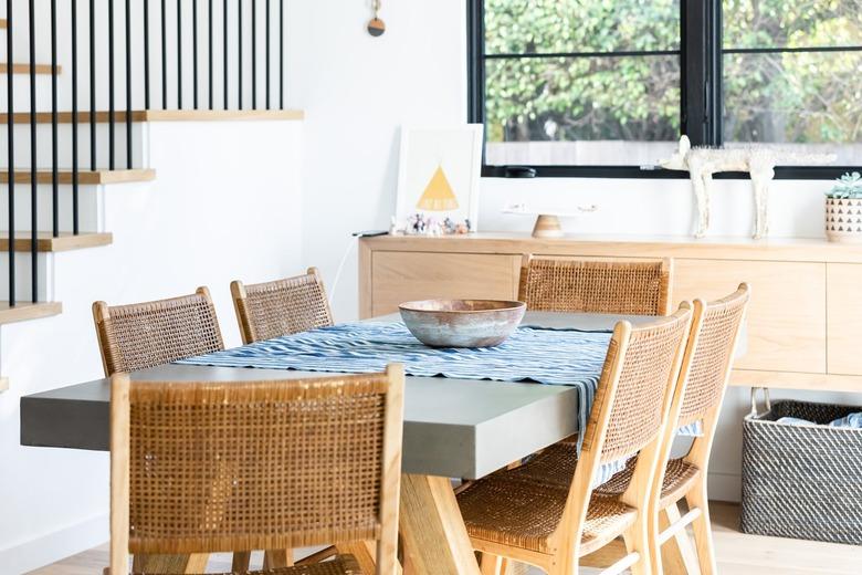 Wood dining furniture next to stairs in a dining room with window and staircase