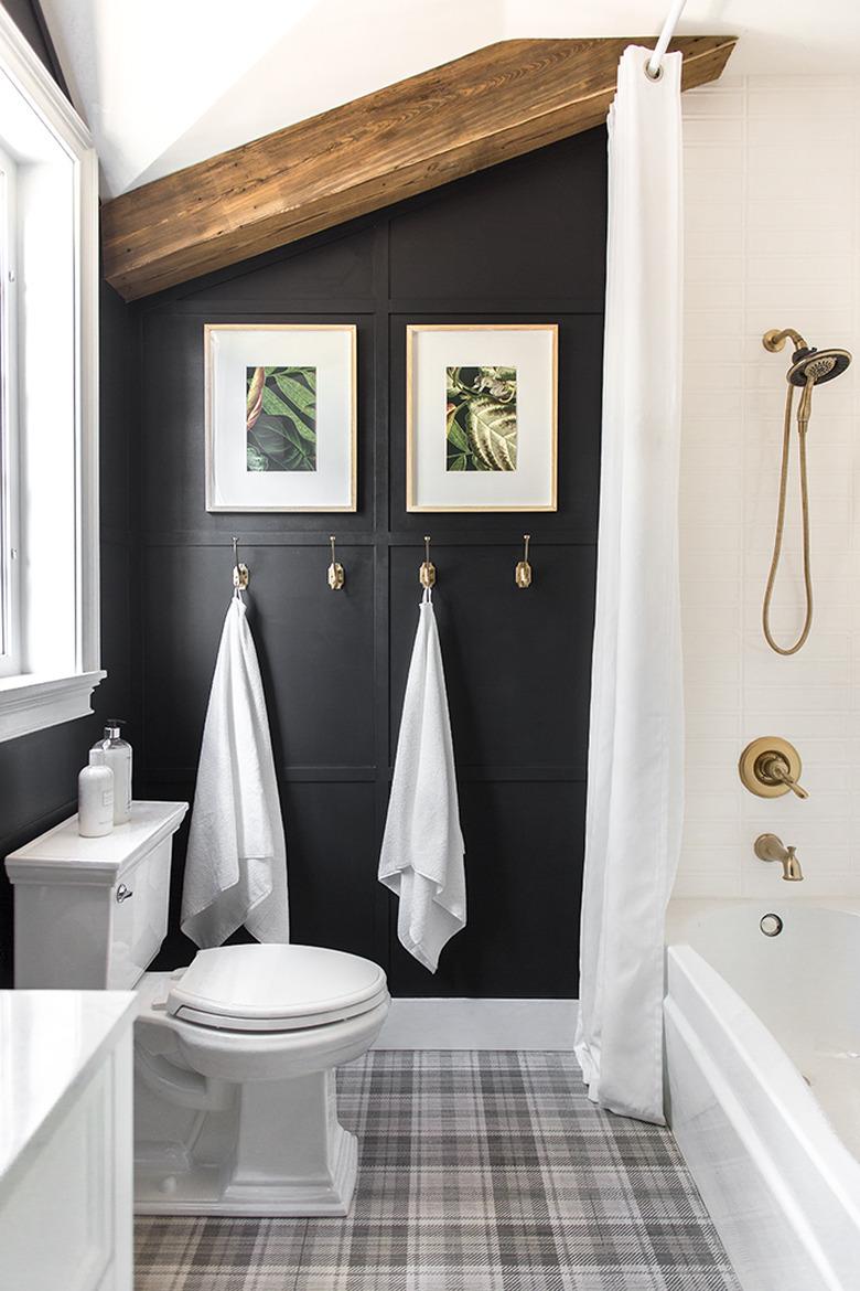 Brass plumbing fixtures in white shower with black wall in bathroom